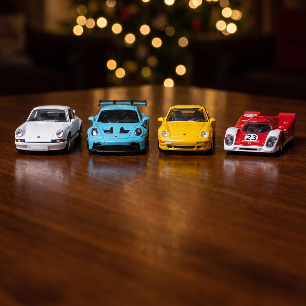 Four 1:64 die-cast cars in front of the Christmas tree